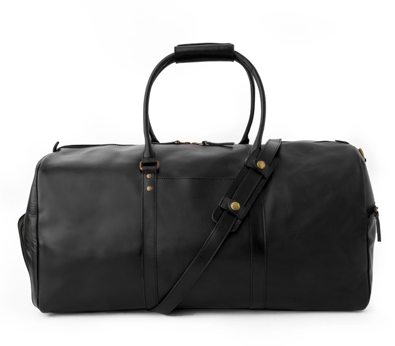 May include: A black leather duffel bag with a top handle and a shoulder strap. The bag has gold-colored hardware and a zipper closure.