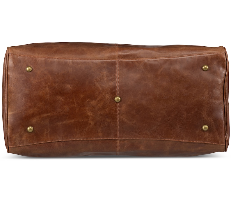 May include: A brown leather duffel bag with brass accents. The bag has a smooth, worn leather texture.