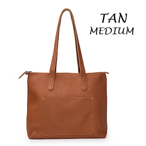 May include: Tan leather tote bag with a zipper closure and a front pocket.  TAN MEDIUM is written in black text on a white background.