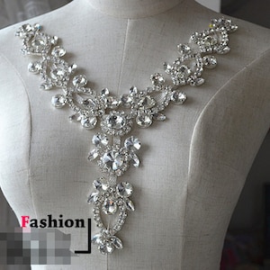 Könnte beinhalten: Eine silberne Strassverzierung mit Blumenmuster. Die Verzierung ist perfekt, um Kleidung, Accessoires oder Wohnaccessoires mit Glanz zu versehen.