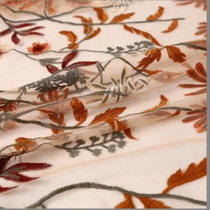 May include: Beige sheer fabric with embroidered floral designs in shades of orange, brown, and green.