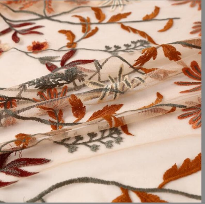 May include: Beige sheer fabric with embroidered floral designs in shades of orange, brown, and green.