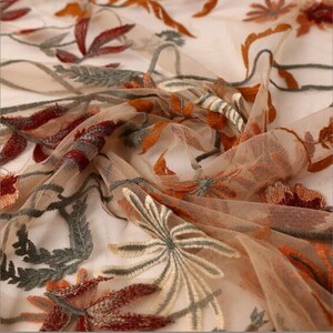 May include: Beige sheer fabric with embroidered floral designs in shades of orange, red, and green.