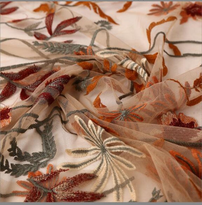 May include: Beige sheer fabric with embroidered floral designs in shades of orange, red, and green.