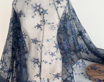 May include: Black sheer fabric with a star pattern embroidered in blue and green. The fabric is translucent and has a delicate texture.