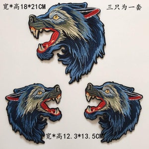 Könnte beinhalten: Drei gestickte Bügelbilder mit einem blauen Wolfskopf mit roten Zähnen und gelben Augen. Das größte Bügelbild misst 18 cm x 21 cm. Die kleineren Bügelbilder messen 12,3 cm x 13,5 cm. Der Text "三只为一套" ist auf dem Bild sichtbar, was im Deutschen "Drei für ein Set" bedeutet.
