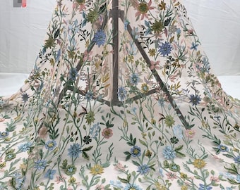 May include: Floral embroidered tulle fabric with a delicate pattern of blue, pink, and yellow flowers on a sheer white background.
