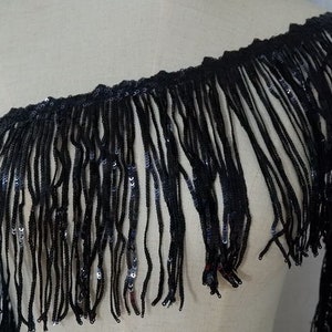 May include: Black fringe trim with sequins. The fringe is about 3 inches long.