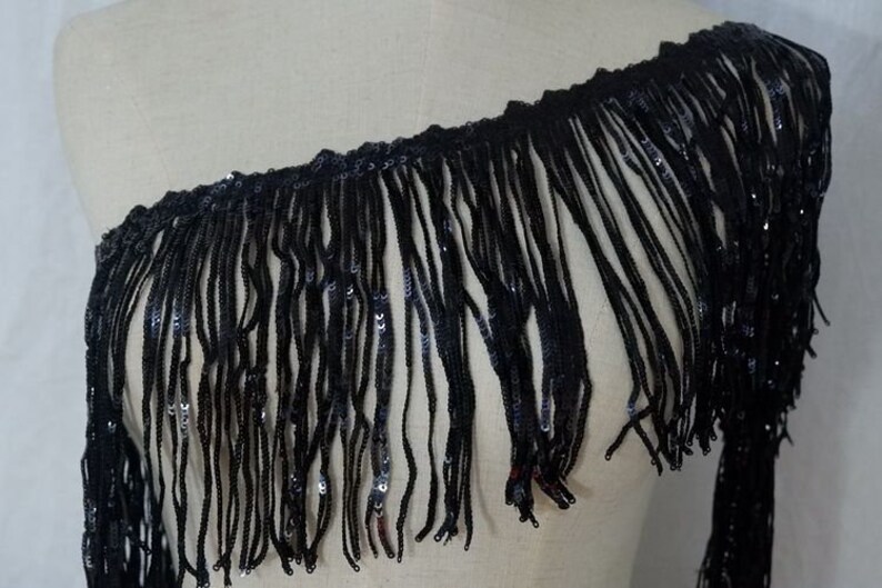 May include: Black fringe trim with sequins. The fringe is about 3 inches long.