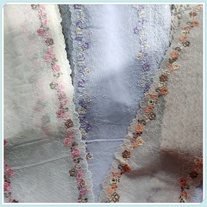 May include: Three pieces of sheer fabric with delicate floral lace trim in shades of white, pink, and purple.