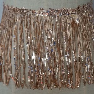 May include: Gold sequined fringe trim with a metallic sheen. The fringe is approximately 2 inches long.