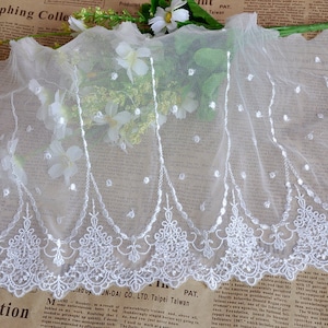 May include: White lace trim with a scalloped edge and delicate floral embroidery. The lace is sheer and has a subtle shimmer.