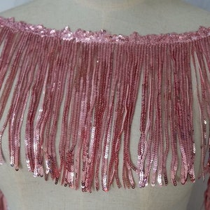May include: Pink sequined fringe trim with a delicate, shimmering finish. This trim is perfect for adding a touch of glamour to any project.