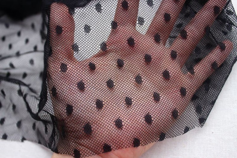May include: Black sheer fabric with small black polka dots. The fabric is delicate and has a soft texture.