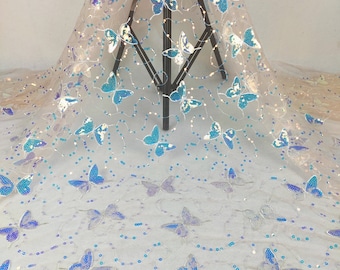 May include: A sheer white fabric with a blue butterfly pattern and iridescent sequins. The fabric is perfect for crafting, sewing, and creating unique projects.