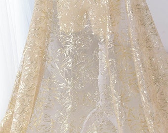 May include: Gold glitter floral lace fabric. The fabric has a sheer, delicate texture with a gold glitter pattern of flowers.