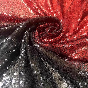 Peut inclure: Tissu de sequins rouge, noir et argent avec un effet dégradé. Le tissu est plié et drapé, montrant les différentes couleurs et textures.