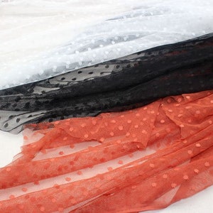 May include: Three pieces of dotted mesh fabric in white, black, and orange. The fabric is soft and sheer, with a delicate polka dot pattern.