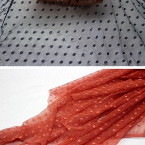 May include: Two pieces of black and orange dotted mesh fabric. The fabric is sheer and has a delicate texture.