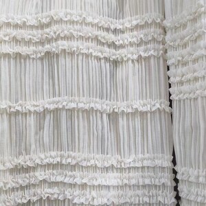 May include: White sheer fabric with a ruffled texture. The fabric is pleated and has a delicate, airy feel.