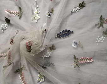 May include: White tulle fabric with embroidered floral designs in shades of pink, blue, and green.
