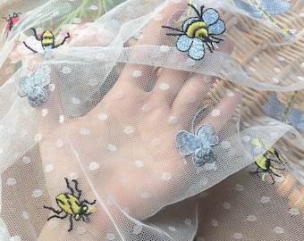 May include: White sheer fabric with embroidered bees and butterflies. The fabric has small white polka dots.