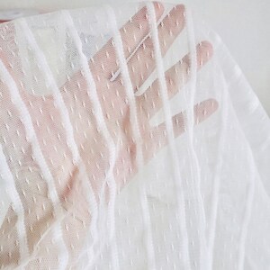 May include: White sheer fabric with a dotted and striped pattern. The fabric is delicate and has a soft texture.