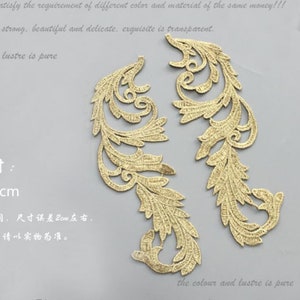 May include: Two gold-colored lace appliques with a delicate floral design. The appliques are about 2 inches tall and are perfect for adding a touch of elegance to any project.
