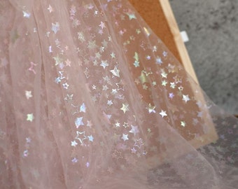 May include: White sheer fabric with iridescent stars printed on it. The fabric is translucent and has a soft, delicate texture.