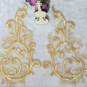 Pode incluir: Dois apliques florais bordados a ouro com intrincados desenhos em espiral. Os apliques são perfeitos para adicionar um toque de elegância a roupas, artesanato ou decoração de casa.