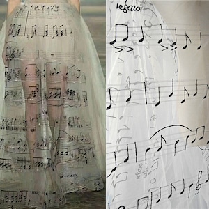 以下が含まれることがあります： 黒い楽譜がプリントされた透き通った白いドレス。ドレスは軽量の生地で作られており、流れるようなシルエットです。楽譜はさまざまなサイズとスタイルでプリントされており、ユニークで目を引くデザインになっています。