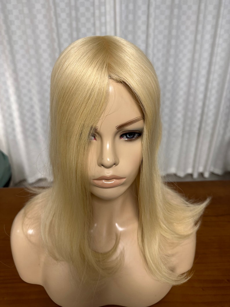 Puede incluir: Un topper de cabello humano rubio con un estilo recto y en capas. El topper est&aacute; dise&ntilde;ado para agregar volumen y longitud a la coronilla de la cabeza.