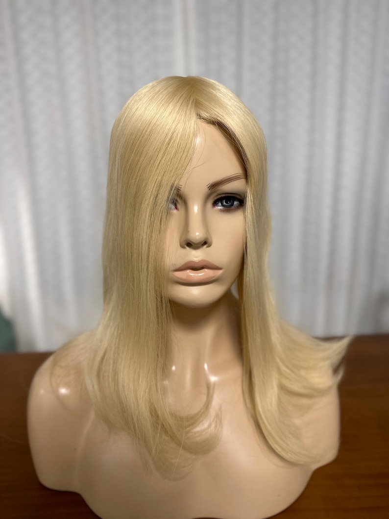 Puede incluir: Un topper de cabello humano rubio con un estilo recto y en capas. El topper est&aacute; en una cabeza de maniqu&iacute; y tiene un aspecto natural y realista.