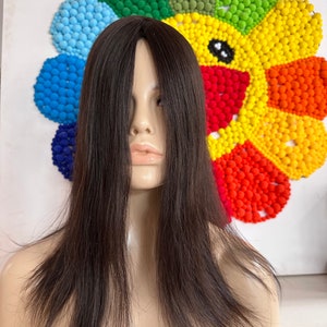Op de afbeelding: Een lang, recht, zwart haarstuk op een mannequinhoofd. Het haarstuk is gestyled met een middenscheiding en valt tot aan de schouders.