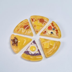 Puede incluir: Seis porciones de pizza en miniatura dispuestas en círculo. Cada porción presenta ingredientes distintos, como una cara de oso marrón, un huevo frito sobre corteza morada, cubos de queso amarillo, pepperoni rojo y bayas azules brillantes.