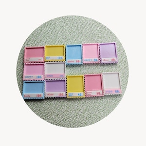 May include: A collection of 12 colourful plastic stamps with different phrases and numbers. The stamps are in various colours, including pink, yellow, blue, and purple. The phrases on the stamps include "Good Luck", "Nice Day", "Smile", "Happy", "Hello", and "YYDS". The numbers on the stamps are 80 and 100.