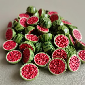 Könnte beinhalten: Ein Haufen Miniatur-Wassermelonen, geschnitten und ganz. Die Wassermelonen haben eine grüne Schale mit dunkelgrünen Streifen, leuchtend rotes Fruchtfleisch und schwarze Samen. Wahrscheinlich Dekorationsartikel.