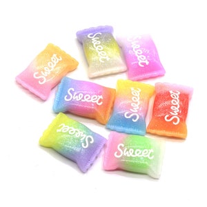 May include: Assortment of eight colorful candy-shaped resin charms with glitter and the word "Sweet" written on each one.