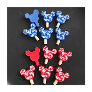 May include: A collection of 10 red and blue Mickey Mouse head shaped lollipops with white swirl designs. The lollipops are arranged in two rows on a black surface.