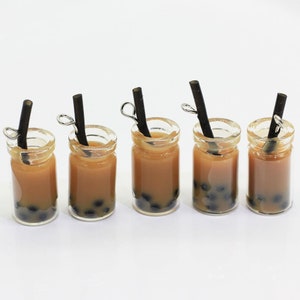 May include: Five miniature glass jars filled with brown liquid and black boba pearls, each with a black straw and a silver hook.