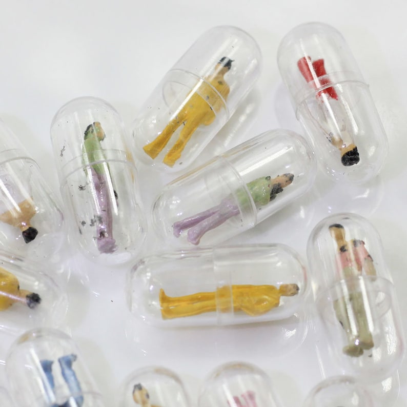 Op de afbeelding: Een verzameling doorzichtige capsules met miniatuurfiguren erin. De figuren zijn gekleed in verschillende kleuren en stijlen, waaronder geel, rood, groen en roze.