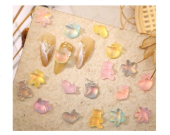 May include: Assortment of colourful iridescent resin nail charms in various shapes, including stars, bears, hearts, and fruit. The charms are small and perfect for adding a touch of whimsy to your nail art.