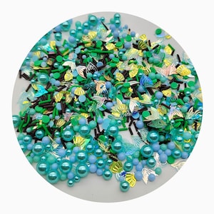 Saupoudrer la décoration de fête d'anniversaire d'une petite fille avec un mélange de faux sucres cristallins, de jumelles, de perles de dragée et de paillettes en forme de queue de poisson