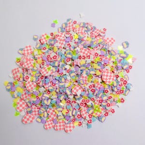 Puede incluir: Un montón de chispas de arcilla polimérica de colores en varias formas. Las chispas incluyen corazones a cuadros, flores, estrellas y otras formas en colores pastel como rosa, amarillo, morado y verde. Ideal para manualidades y nail art.