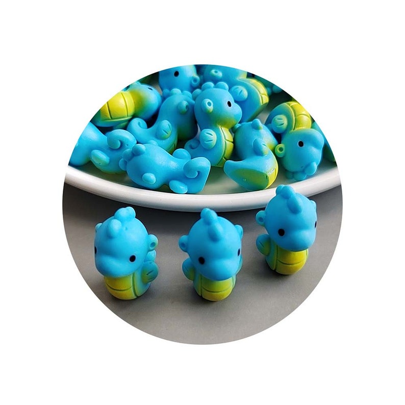 May include: A group of blue and yellow seahorse shaped charms. The charms are made of plastic and have a glossy finish.