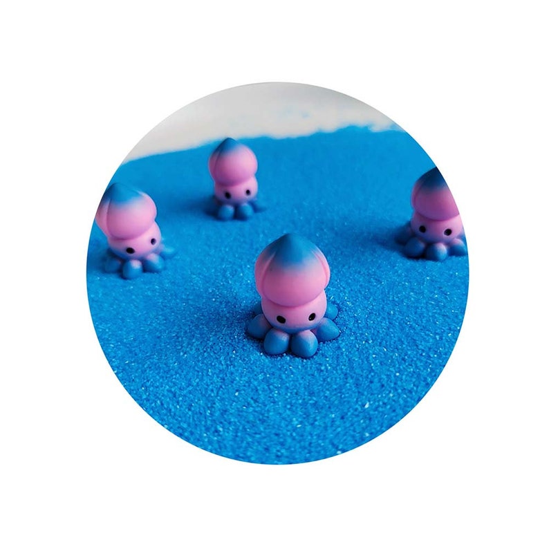 May include: Four small pink and blue octopus figurines on a blue sparkly surface.