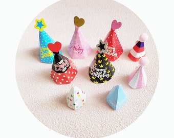 May include: Assortment of colorful party hats with different designs and text, including "Happy Birthday" and "Birthday".