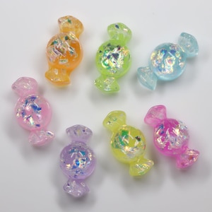 May include: Assortment of eight iridescent candy-shaped resin charms in various pastel colors, including pink, purple, blue, green, and yellow.