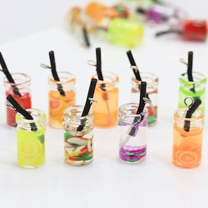 May include: Assortment of miniature glass jars with colourful fruit-themed designs and black straws. The jars are clear and filled with a liquid that appears to be water or juice. The jars are approximately 2.5 cm tall and are perfect for adding a whimsical touch to crafts or jewellery.