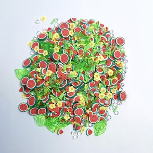 Puede incluir: Una colección de pequeñas rodajas de arcilla polimérica con forma de trozos de sandía, flores amarillas y hojas verdes, mezcladas con diminutos diamantes de imitación transparentes. Las sandías son rojas con corteza verde y semillas negras.